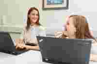 Two people smiling while working on a laptop